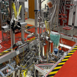 Northwestern University positron-trap apparatus recessed into a laboratory floor, surrounded by metal tubing, cables and support frames.