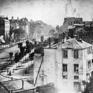 Louis Daguerre’s view of Boulevard du Temple, with a standing customer and a smaller shoeshiner figure near the lower-left street corner.