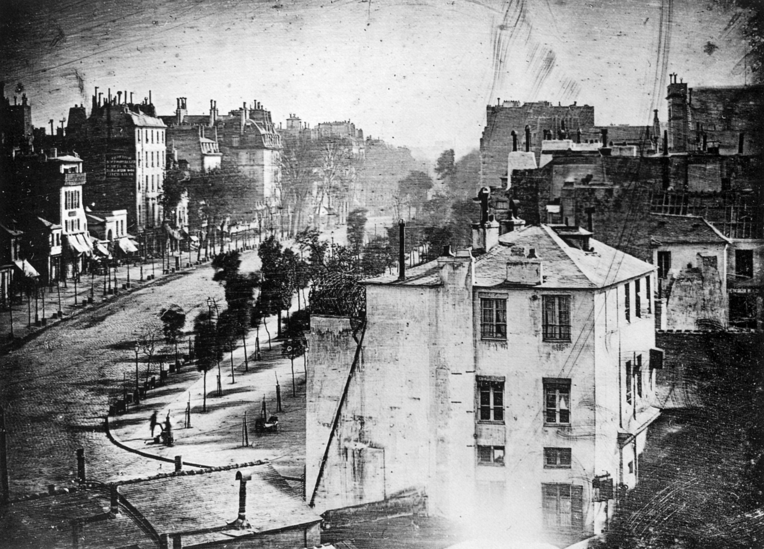 Louis Daguerre’s view of Boulevard du Temple, with a standing customer and a smaller shoeshiner figure near the lower-left street corner.