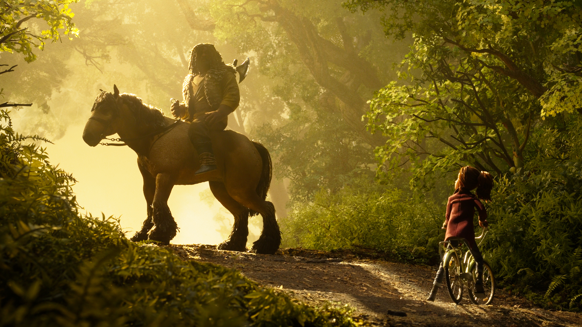 Brendan rides a horse through a sunlit forest as Prue stands beside her bicycle in Wildwood.