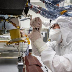 Technician Emory Toomey installs a navigation camera on NASA’s Dragonfly rotorcraft in a cleanroom