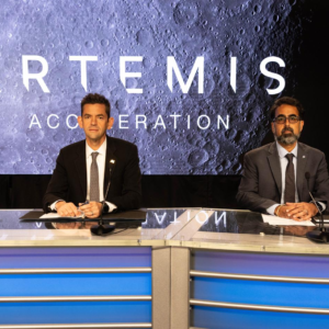 Four NASA leaders seated at the Artemis Acceleration briefing with a Moon graphic behind them
