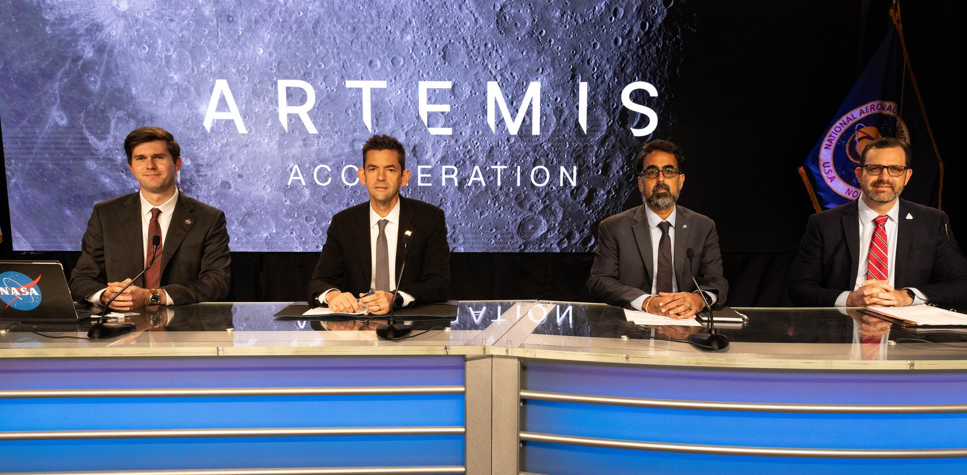 Four NASA leaders seated at the Artemis Acceleration briefing with a Moon graphic behind them